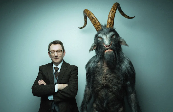 Evil's Leland Townsend and his goat-horned demonic boss stand smugly against a nondescript office wall.