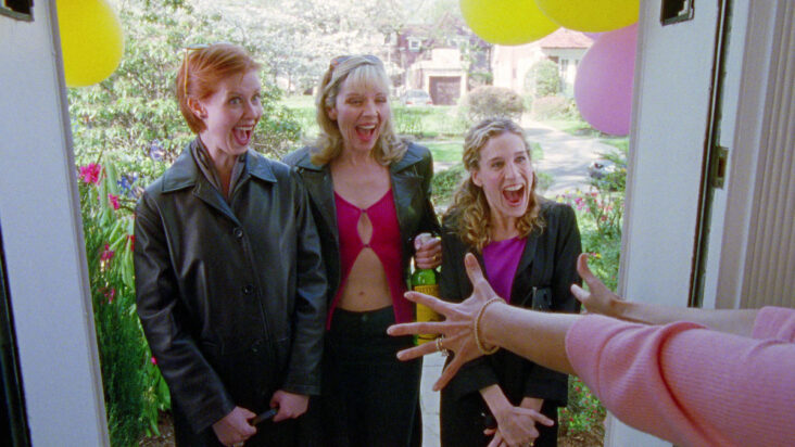 Another still from The Baby Shower shows Miranda, Samantha, and Carrie being greeted at the door of a suburban house, everyone wearing grotesquely huge smiles.