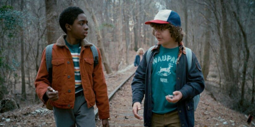 Lucas and Dustin chat and walk through the woods together in a still from Stranger Things.