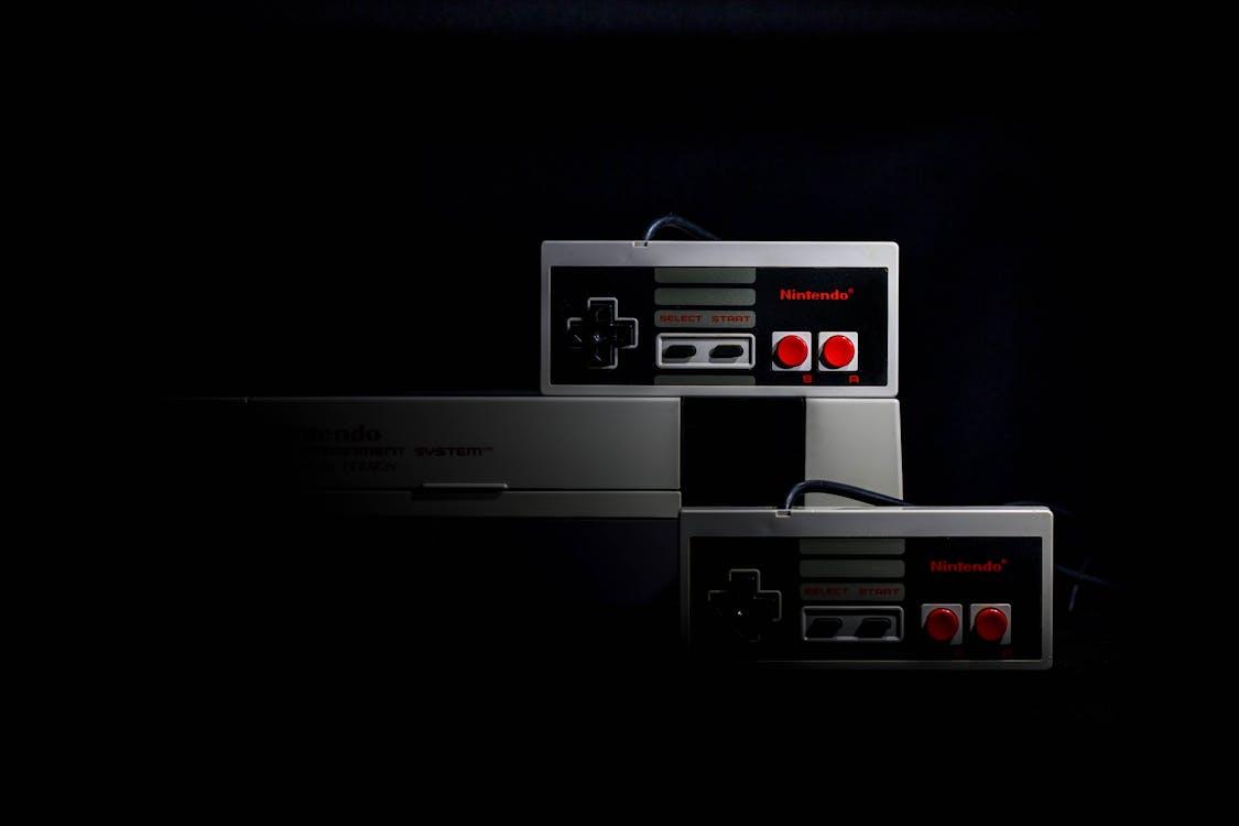 Free Retro gaming controllers from the Nintendo Entertainment System in low-key lighting, evoking nostalgia. Stock Photo
