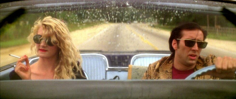 Laura Dern and Nicholas Cage drive down a lonesome highway in a convertible in a scene from Wild at Heart.