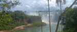 A photograph of a lush landscape in Argentina features a stunningly massive waterfall emptying into a large lagoon flanked by green trees.
