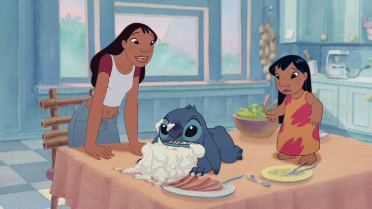 Stitch kneels face-planted in a cake on the kitchen table as Lilo and her big sister Nani try to make sense of the situation.