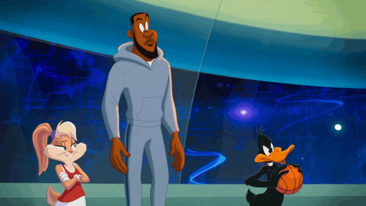 An animated version of LeBron wearing a gray warmup suit stands between Lola Bunny and Daffy, who holds a basketball. LeBron looks rather dubious about the whole situation.