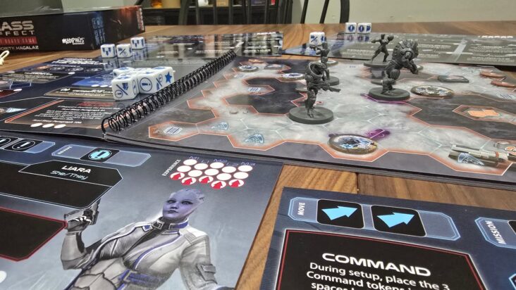 A view of Mass Effect: Priority Hagalaz being played in media res, with dice, a rulebook, and spacey miniatures scattered across the table.
