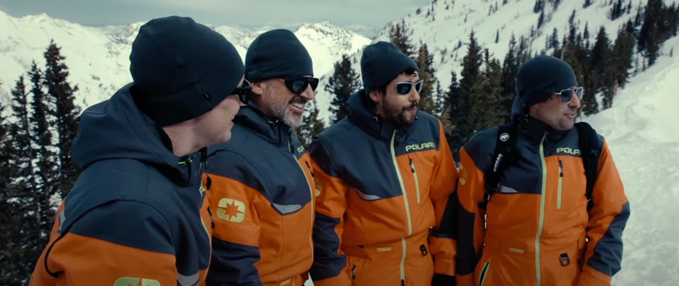 A still from Mountainhead shows the four main characters arm-in-arm in day-glo orange ski coats on the side of a snowy mountain.