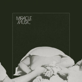 Album art for Grails' Miracle Music is a black-and-white photo of a man bent forward with his hands tied behind his back, shirt riding up to reveal skin. Two other men's arms reach from outside the frame to hold on to his shackles.