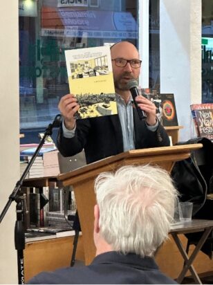 Jordan Mechner holds up a page from his graphic memoir, Replay, at an event at Greenlight Books.