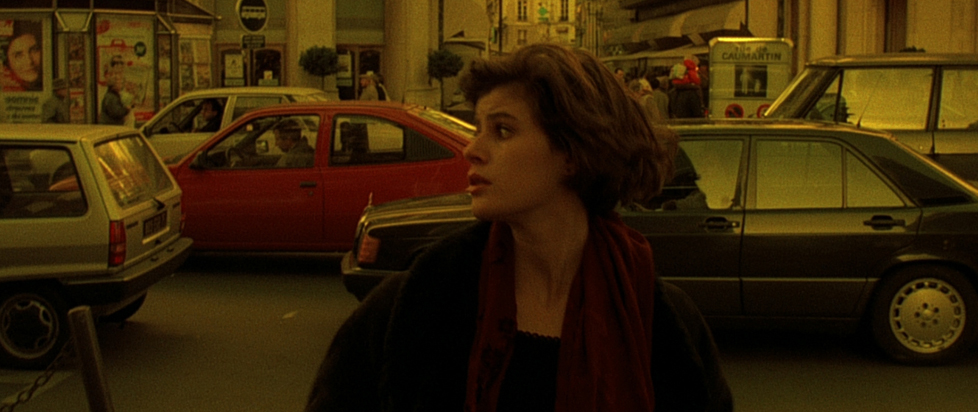 A still from The Double Life of Veronique shows a stylish young woman crossing a street, face turned to the side to watch for oncoming traffic.