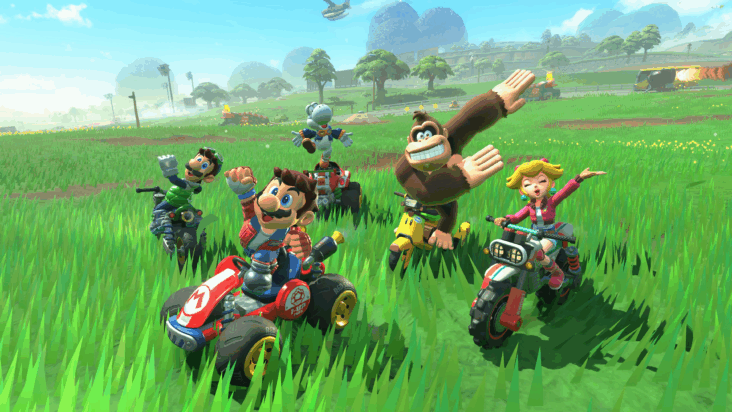 A screenshot from Mario Kart World shows Mario and a bunch of other racers cheering from a field of tall grass.