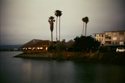 A scan of a photo Matthew shot on his Nikon F2 camera, a bungalo with a few palm trees on the bank of a river during a hazy sunset