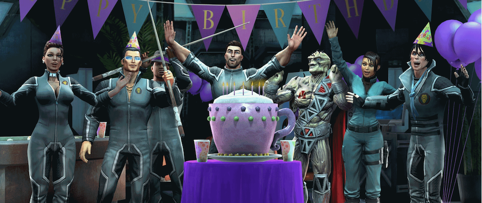 A screenshot from Saints Row IV where a bunch of folks are around a birthday cake in the shape of a giant mug everyone cheering for the camera