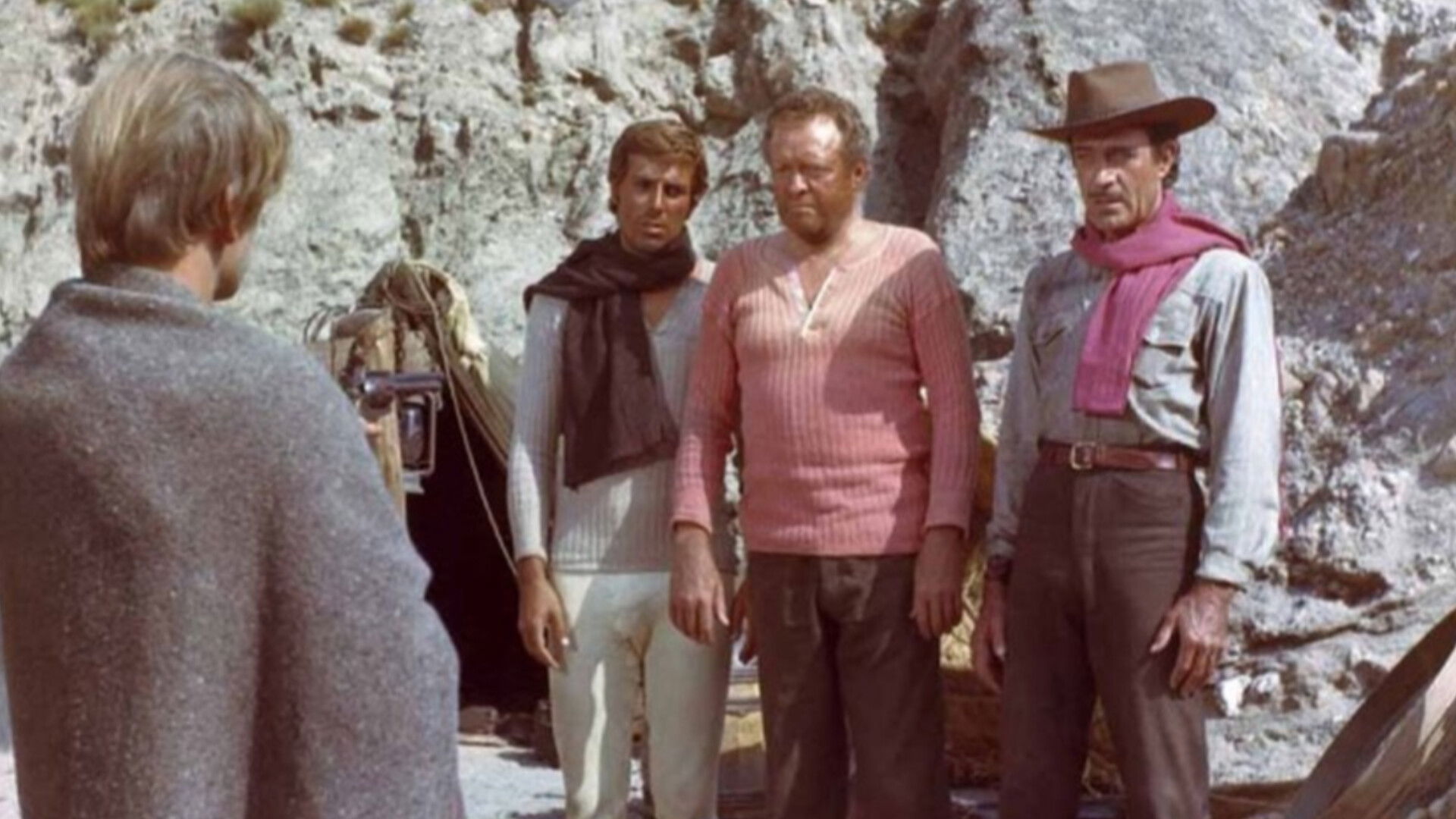 In a scene from The Ruthless Four, four men stand around a desert looking at each other while wearing fabulous scarves and ponchos for some reason.
