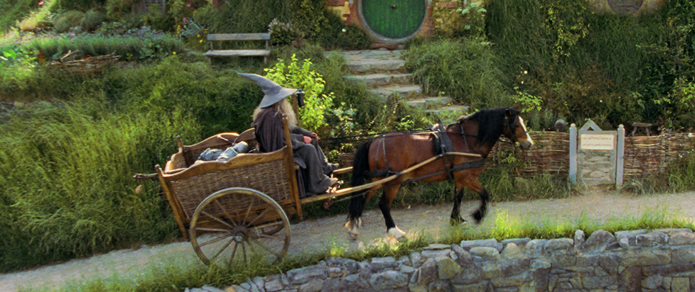 Gandalf approaches the hilly Shire in a rickety horse-drawn wagon.