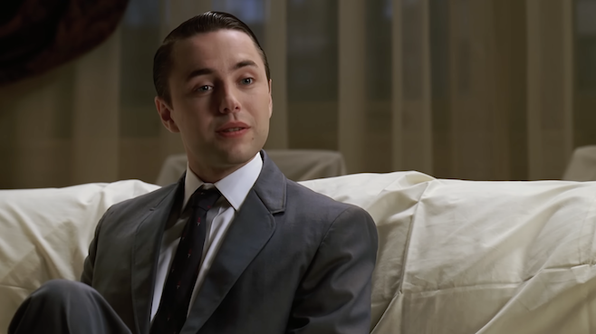 Another picture of Pete, sitting on a couch with a curtain over it, looking like a good boy
