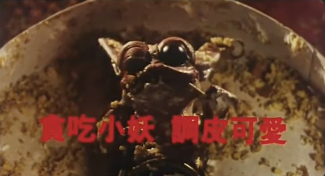 A screenshot from the trailer of Saga of the Phoenix featuring Tricky Ghost as a puppet with big black eyes picking food out of its teeth it's pretty gross