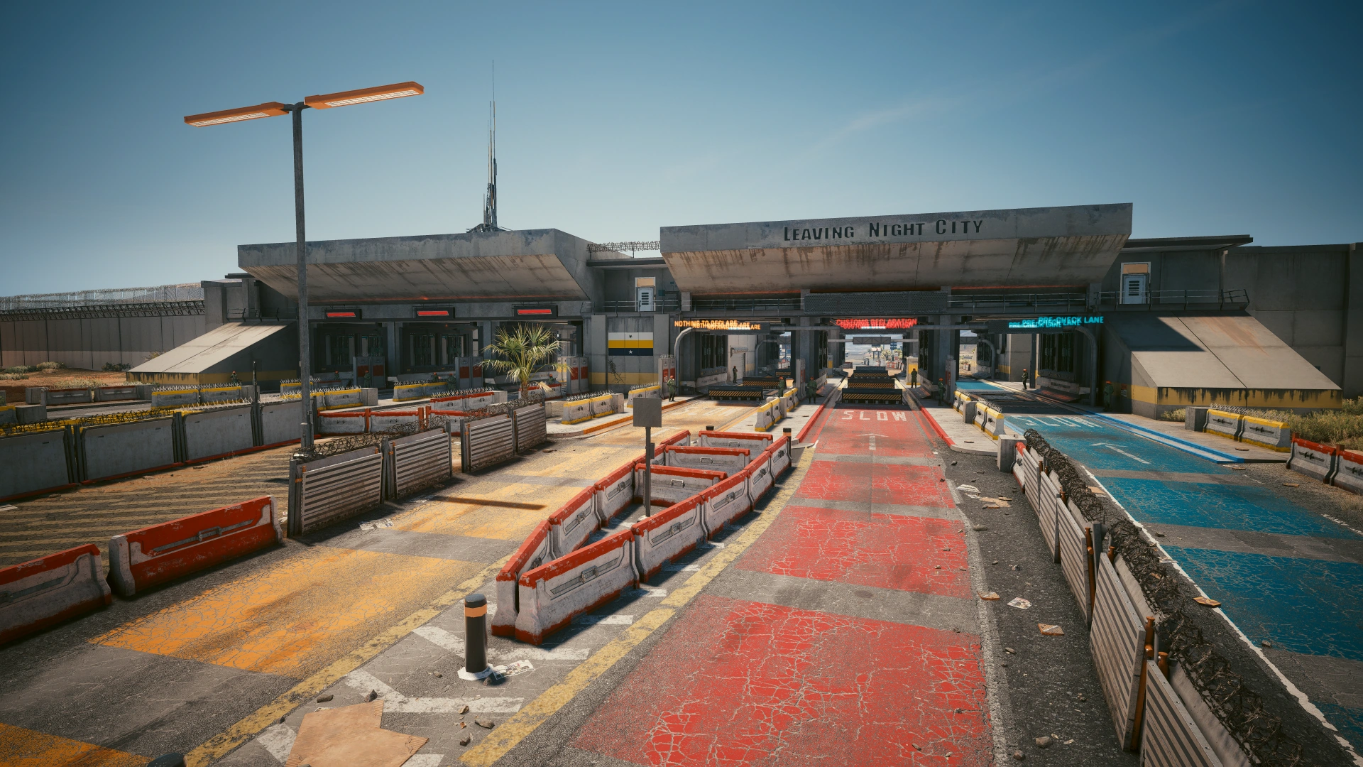"A sunny daytime view of the SoCal Border Crossing checkpoint from the video game Cyberpunk 2077, showing a sign that reads 'Leaving Night City'"