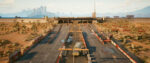 A wide shot of a desert landscape with a multi-lane highway leading to a large border crossing checkpoint.