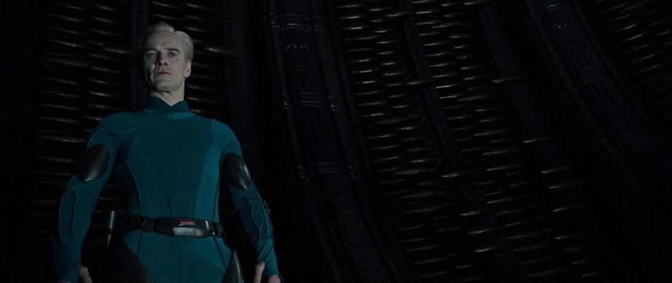 A screenshot of Alien Covenant where Blond David in a blue little uniform is looking down disdainfully at us, the viewer