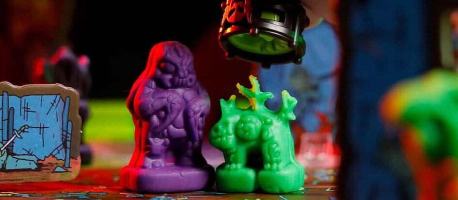 A photograph of two clay minis from Necromolds a purple bug guy and a green lizard that is about to get smooshed