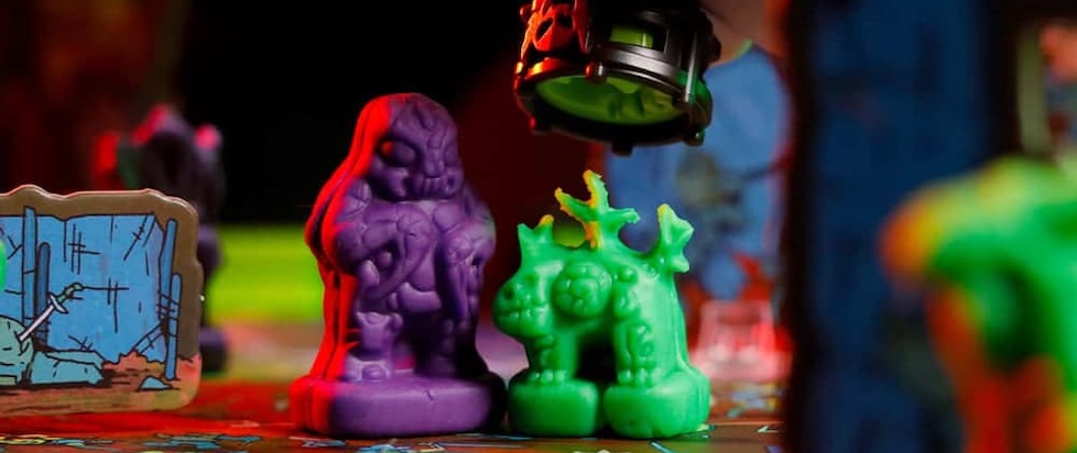 A photograph of two clay minis from Necromolds a purple bug guy and a green lizard that is about to get smooshed