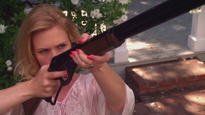 A screenshot from Mad Men where Betty is holding Chekov's BB gun and aiming down the sight with pink nails and a pink nightie in full gamer mode