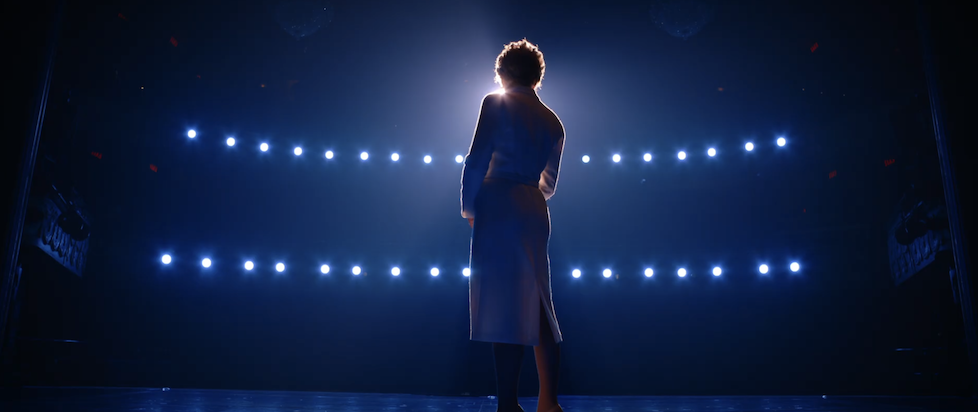 A screenshot from Netflix's trailer for Diana with the title character in white facing the lights in blue shadow