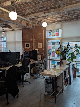 A photograph of the Gumbo working space with exposed brick and lots of computers and good lighting and green plants