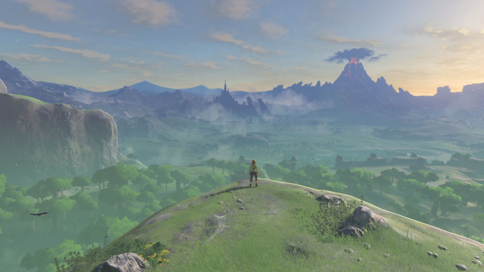 Link stands at the edge of a cliff, looking over the vast landscape in Breath of the Wild.