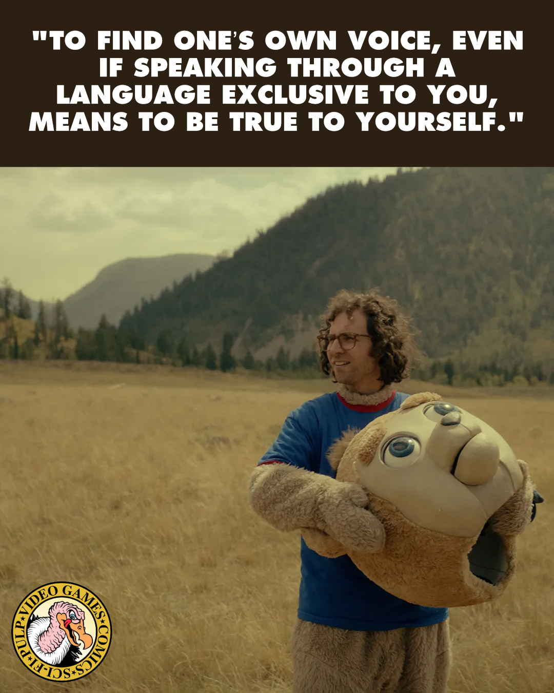A screenshot from Bigsby Bear where a young person in a bear mascot costume with a blue shirt on is holding the bear head mask and standing in yellow grass by some mountains. A quote above the image reads: "To find one’s own voice, even if speaking through a language exclusive to you, means to be true to yourself."