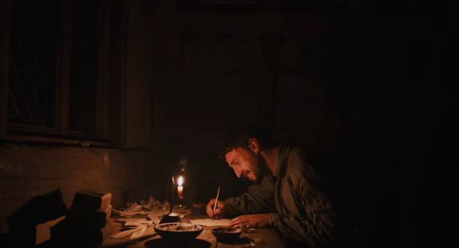 An image from Hamnet where Shakespeare is writing at night by candlelight but looking like he's pleased with what he's got going on
