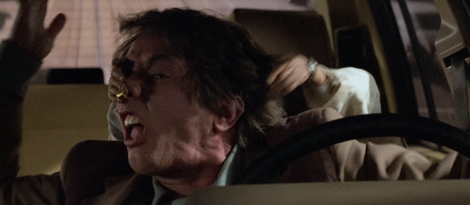 A screenshot from the trailer of Innerspace where Martin Short is trying to drive but someone is grabbing his face from behind