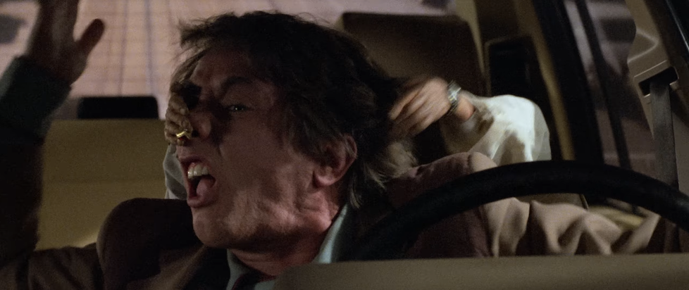 A screenshot from the trailer of Innerspace where Martin Short is trying to drive but someone is grabbing his face from behind