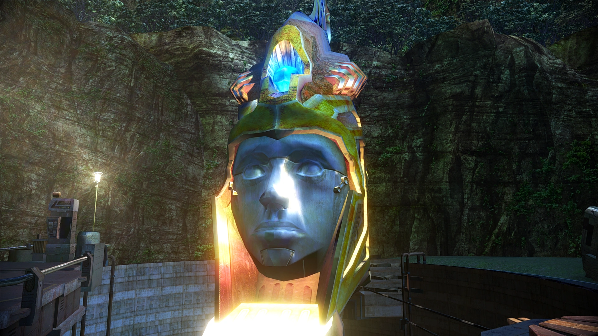A screenshot from FFXIII showing a massive, stoic humanoid face made of a metallic, bluish stone. It wears an ornate, glowing crown or headdress with intricate gold and red patterns, topped with a glowing blue crystal.
