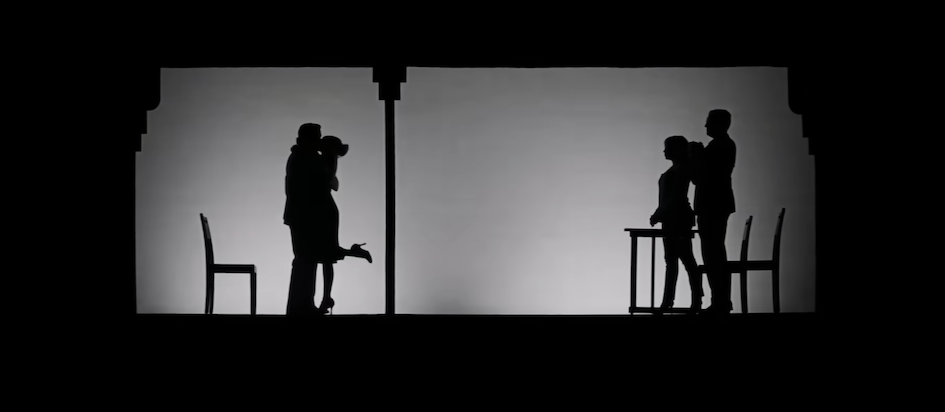 A screenshot from the trailer for La La Land with a scene from a theater in black and white silhouette with two characters kissing on the left and two others looking on the right
