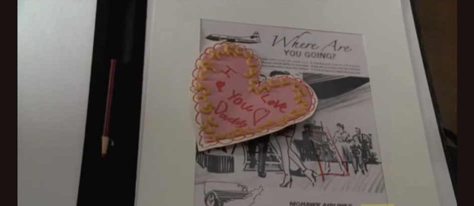 A screenshot from Mad Men where a child-made valentine that says I Love you Daddy in a pink heart surrounded by macaroni sits atop an ad design sketch saying Where are you going