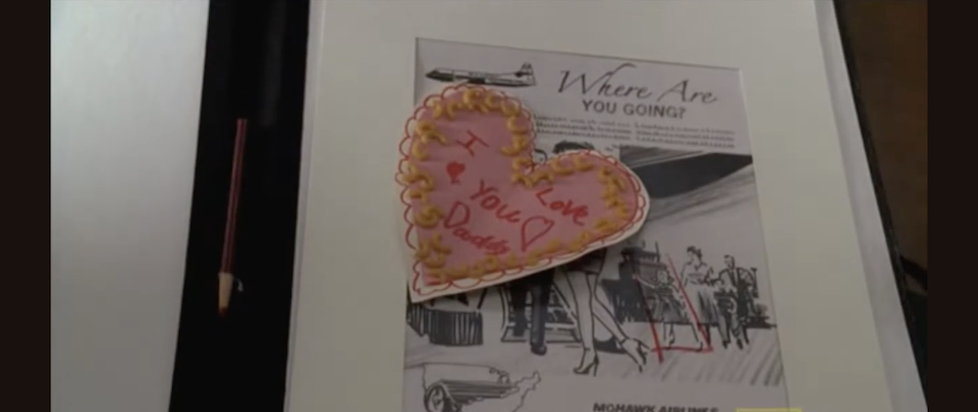 A screenshot from Mad Men where a child-made valentine that says I Love you Daddy in a pink heart surrounded by macaroni sits atop an ad design sketch saying Where are you going