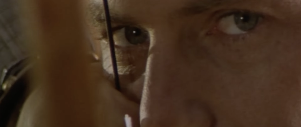 A screenshot from the trailer of Robin Hood Prince of Thieves with a very extreme closeup of Kevin Costner's dreamy eyes as he pulls a bowstring to his cheek
